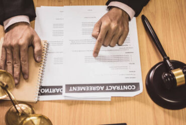 Hand businessman or lawyers sitting office Pointing contract papers on wood table. Law of advisor Concepts and vintage, Sunset light.Selective Focus