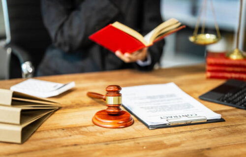 A young businesswoman is working at her desk, diligently preparing legal briefs and reviewing evidence for an upcoming trial, demonstrating her expertise as a lawyer in litigation and advocacy.